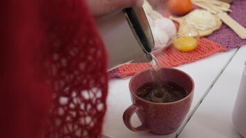 POV pouring black tea into a pink mug on a white wooden table at cafe. video