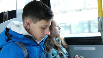 Interior of crowded bus with passengers listening to music and using mobile phone. two teenagers in blue clothes sit on a bus Canada Vancouver hoods autumn winter spring tracksuits use a mobile phone video