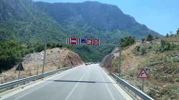 view from the window of the mountains of Albania passing vehicles on the road light cloudy sky summer route travel trip video