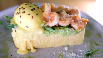 breakfast toast with avocado and egg shrimp Parmesan greens appetizing aromatic lunch snack sprinkled with flax grains seeds on gray plate restaurant serving dipping shrimp egg yolk several s video