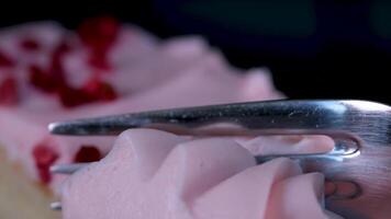 en mangeant cheesecake avec une fourchette. prise mordre de cheesecake. sucré dessert nourriture proche en haut de une rose fraise gâteau tourbillonnant sur une blanc plaque. video