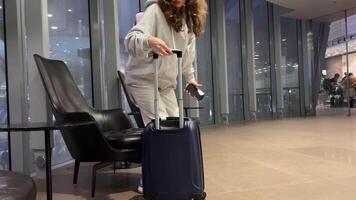 Attractive young blonde woman pulling her suitcase and talking on the phone. Stylish outfit, formal wear. Being busy, business trip. Successful lifestyle. video