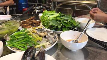 Vietnamese food shells mussels fish cooking Vietnamese soup with green leaves and pieces of meat video