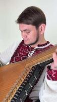 Mann 30-35 Jahre alt im Hände mit Musical Instrument kobzone vorbereiten zu abspielen Blau Augen rot Stickerei Bart ordentlich Frisur im Rollstuhl Kämpfer Musiker Krieg Veteran Konsequenzen von Krieg Leben geht auf video