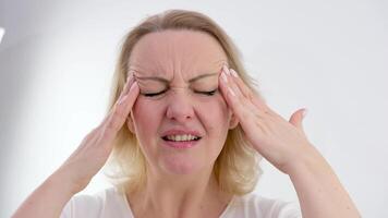 Portrait of a beautiful tired girl with a headache, rubs her temples with her hands, woman's stress, close-up isolated on white background video