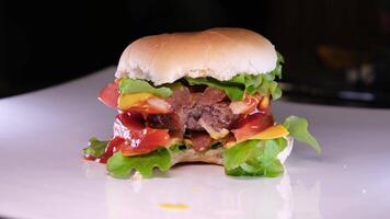 Overhead Schuss von gebissen Burger im Brötchen auf Weiß Teller mit Kopieren Raum. lecker heiß hausgemacht schnell Essen Mahlzeit. video