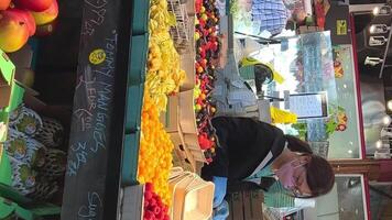 granville ilha 2 ásia meninas dentro máscaras e luvas trabalhos às a bazar. elas vender frutas e vegetais, uma muitos do framboesas, mangas e de outros lindo bagas video