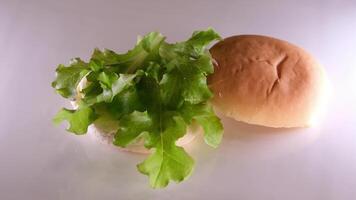 falten ein Burger erstellen ein Burger Startseite mit ein Brötchen stellen Zwiebel Schnitzel Tomate gießen Senf Ketchup stellen Käse und Grüner Salat Verbreitung Mayonnaise auf das Brötchen das ganze Prozess im anders s video