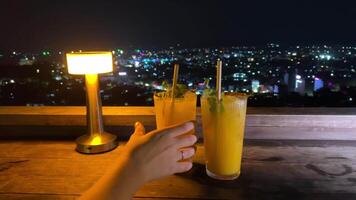 mans Hand pflücken oben Cocktail Glas beim Tabelle zwei Gläser, Bar Snacks beim Dämmerung glücklich Stunde, luxuriös Privat Resort Restaurant. video