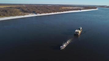 antenne visie van een aak drijvend Aan een breed rivier- Verleden de herfst weiden. klem. de lading schip draag- goederen Bij een bevaarbaar rivier. video