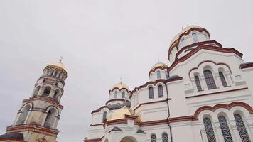 Aussicht von unten von historisch Russisch Kirche. Aktion. Weiß Kirche mit alt Glocke Turm auf Hintergrund von wolkig Himmel. Außen von schön alt Kirche video