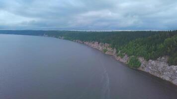 Top view of rocky shore of lake with forest. Clip. Panorama of lake with rocky shore on background of green forest and horizon. Calm lake on background of endless forest on cloudy day video