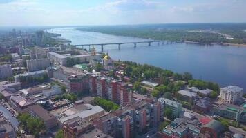 Aerial view of the city located in picturesque area on a summer day. Clip. A church with the golden dome, a river and city houses with the forested terrain. video