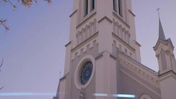 botten se av en skön Fasad av en historisk byggnad på en blå himmel bakgrund. handling. gammal kyrka byggnad med en torn. video