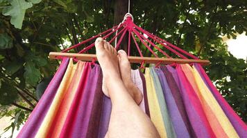 4K of a person's feet swinging while lying in a colorful hammock video