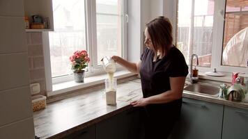 vrouw gieten meel in een plastic container, een vrouw in de keuken. video