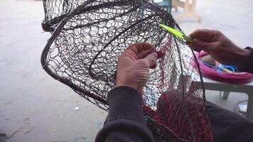hamn fiskare reparation fisk fångst bur med fiske netto nål antal fot. video