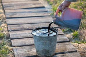 Pour used motor oil from a can into a metal bucket. photo