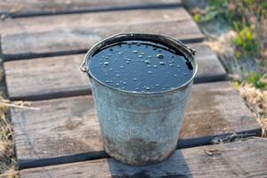 Used car motor oil in a metal bucket. photo