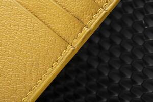 Part of a yellow leather wallet business card holder on a black background. photo