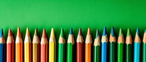 Colourful pencils isolated over green background. Close up image of vibrant pencils for school with empty space for text. photo