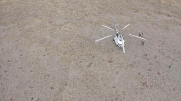 aérien Haut vue de une hélicoptère sur sec sol arrivée à porter secours une petit groupe de personnes. agrafe. économie touristes perdu dans sauvage la nature. video