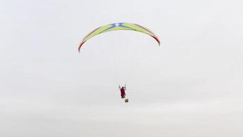 começando do parapente, instrutor com uma vermelho Super homen capa e cliente Aumentar para dentro a ar. Ação. parapentes subindo em nublado céu fundo. video