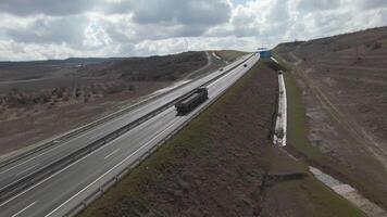 Aerial view of a motorway with driving cars and large cargo truck. Shot. Road built along endless fields on cloudy sky background. video