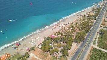 Aerial view of a tropical beach with white sand, green palm trees and blue sea. Clip. Touristic resort on a summer sunny day located by the city with a long road along the coast. video
