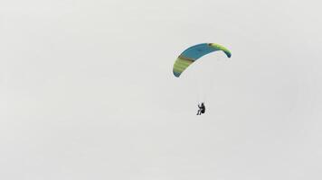 volador paracaidista en contra el nublado cielo. acción. concepto de extremo deporte, emociones y aventura, un hombre con un paracaídas altísimo en el cielo. video