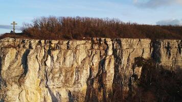 panoramico paesaggio con roccia scogliera e cristiano attraversare su suo picco. sparo. concetto di religione, posto di fede e pace, aereo Visualizza di un' montagna e e un' attraversare. video