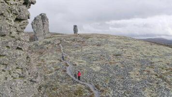 Famous tourist attraction, stone pillars Manpupuner, Komi republic, Russia. Clip. Aerial view of group of hikers exploring breathtaking landmark. video