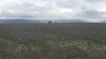 antenn se av en helikopter och en grupp av vandrare på en berg topp. klämma. begrepp av äventyr och turism, människor utforska vild naturlig kuperad område. video