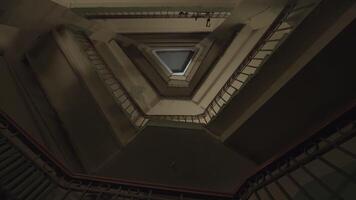 bas vue de le escaliers et beaucoup planchers avec vieux façonné le fer et en bois balustrades. Stock images. Plastique sac en volant le long de le planchers de un inhabituel triangulaire en forme de maison entrée. video