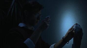 Young man with turned on mobile phone flash fails to turn on the light. Stock footage. Man turning on and off a switcher on the wall in a dark room, blackout concept. video