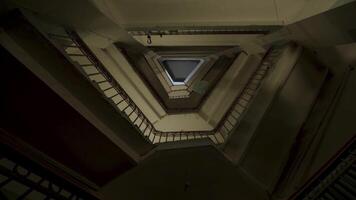 Bottom view of the stairs and many floors with old fashioned iron and wooden railings. Stock footage. Plastic bag flying along the floors of an unusual triangular shaped house entrance. video