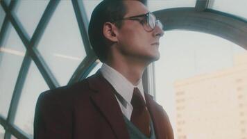 Portrait of a handsome young clever scientist in a classic suit looking pensively through the window and walking away. Stock footage. Academician in a retro scene. video