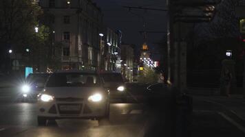 Nacht Sommer- städtisch Aussicht von Selten Autos Fahren langsam auf das Straße. Lager Filmaufnahme. Nacht der Verkehr im das Stadt, ziehen um Autos entlang Gebäude und Häuser auf dunkel Himmel Hintergrund. video