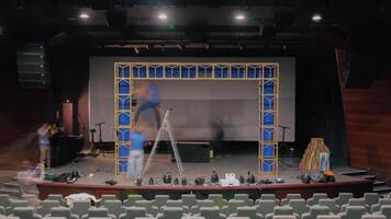 Many people preparing the stage for a performance. . Installation of decorations for the play at the theatre hall. video