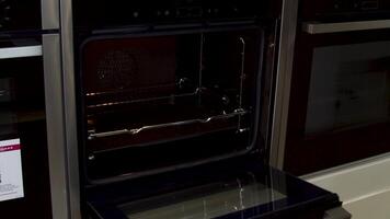 comprador elige un estufa en el cocina a un hogar aparato almacenar. casa utensilios masculino mano prensado un botón y apertura un eléctrico negro horno. video