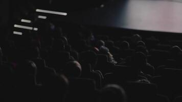 Menschen Sitzung im dunkel Halle und Uhr ein Film. . Rückseite Aussicht von Menschen beim das Kino Halle Aufpassen ein Film aufmerksam, Konzept von Freizeit. video