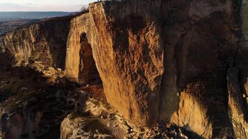 aérien vue de une géant falaise à le coucher du soleil sur une été ensoleillé journée. tir. massif mais ne pas Profond arqué la grotte à l'intérieur Roche formation, magnifique la nature. video