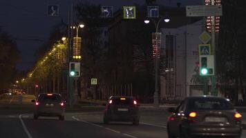 natt sommar urban se av sällsynt bilar körning långsamt på de väg. stock antal fot. natt trafik i de stad, rör på sig bilar längs byggnader och hus på mörk himmel bakgrund. video