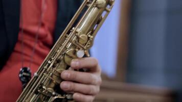 détails de une homme en jouant une d'or saxophone. . proche en haut de une homme dans une foncé costume et une rouge chemise en jouant saxophone pendant performance. video