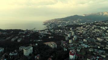 Aerial morning skyline over the city located by the sea. Shot. Breathtaking landscape with a early morning haze above the coastal town and calm water surface. video