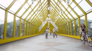Moscow, Russia - July, 2020. Pedestrian bridge with cyclists. Action. Beautiful yellow bridge for pedestrians in city park. Group of cyclists rides on covered bridge for pedestrians video