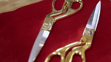Scissors for cutting ribbons during grand openings or celebration of events. . Close up of golden scissors on a red pillow. video