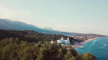 Aerial view of a luxury resort located by the sea. . Flying over the breathtaking hotel surrounding territory with the sea coast, swimming pool, pier, and green forest. video