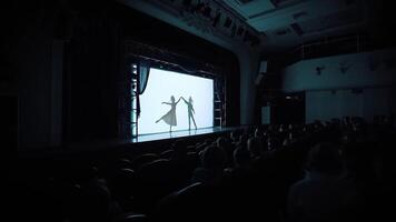 silhuetter av ung man och kvinna praktiserande i klassisk balett piruett på de skede. . mörk konsert hall med publik tittar på balett. video