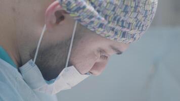 gezicht van professioneel chirurg Bij werk. actie. jong chirurg is concentreren Aan het uitvoeren van operatie onder anesthesie. gemaskeerd chirurg presteert operatie video